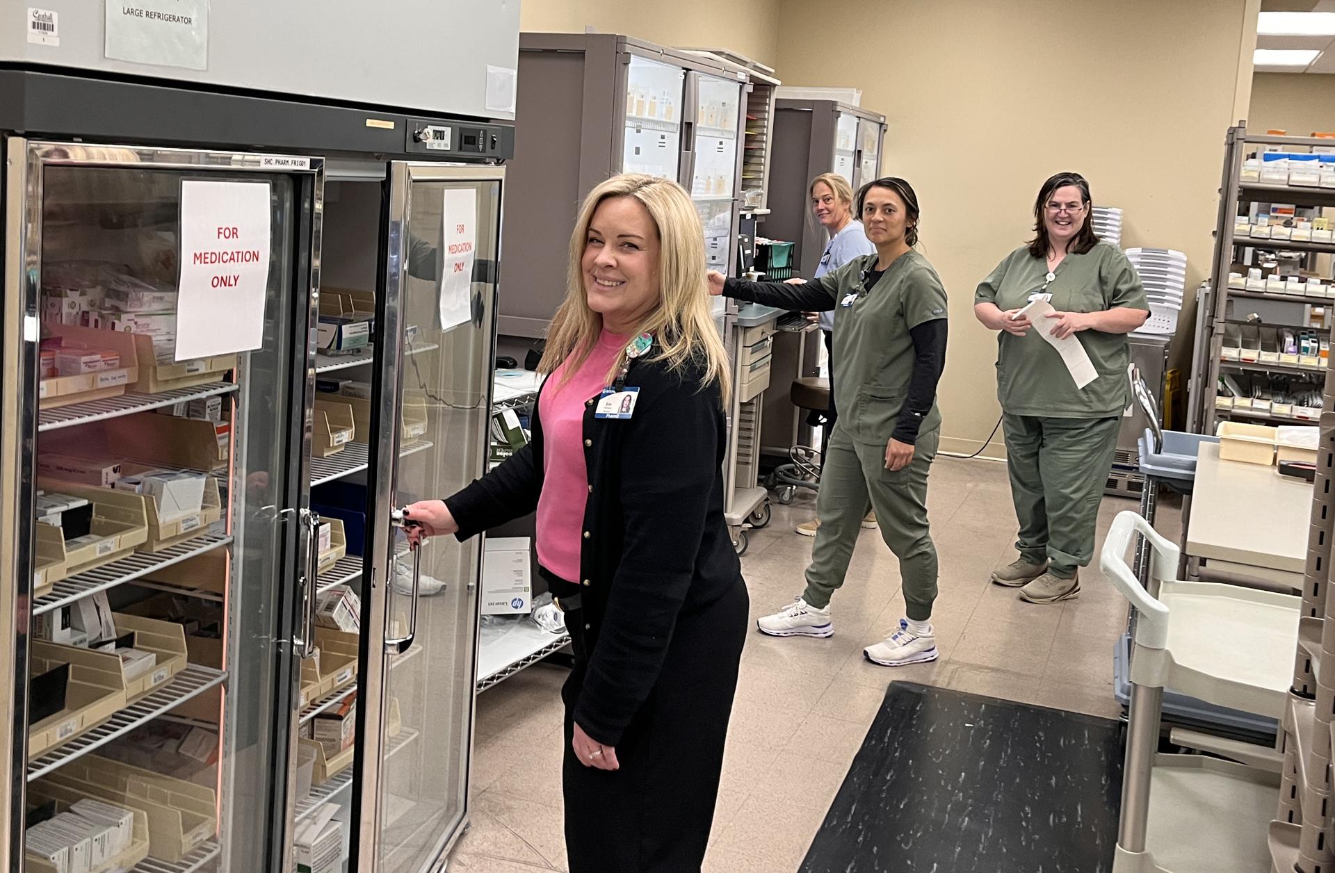 Group of four pharmacy employees working and smiling.