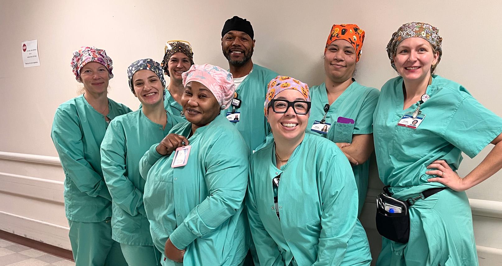 Group of eight smiling operating room registered nurses.